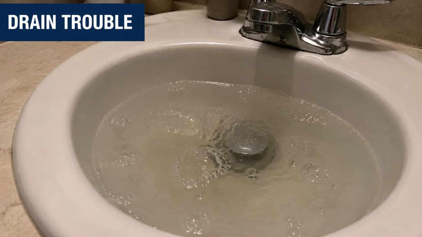 A bathroom sink filled with standing water that is failing to drain properly due to a clog.
