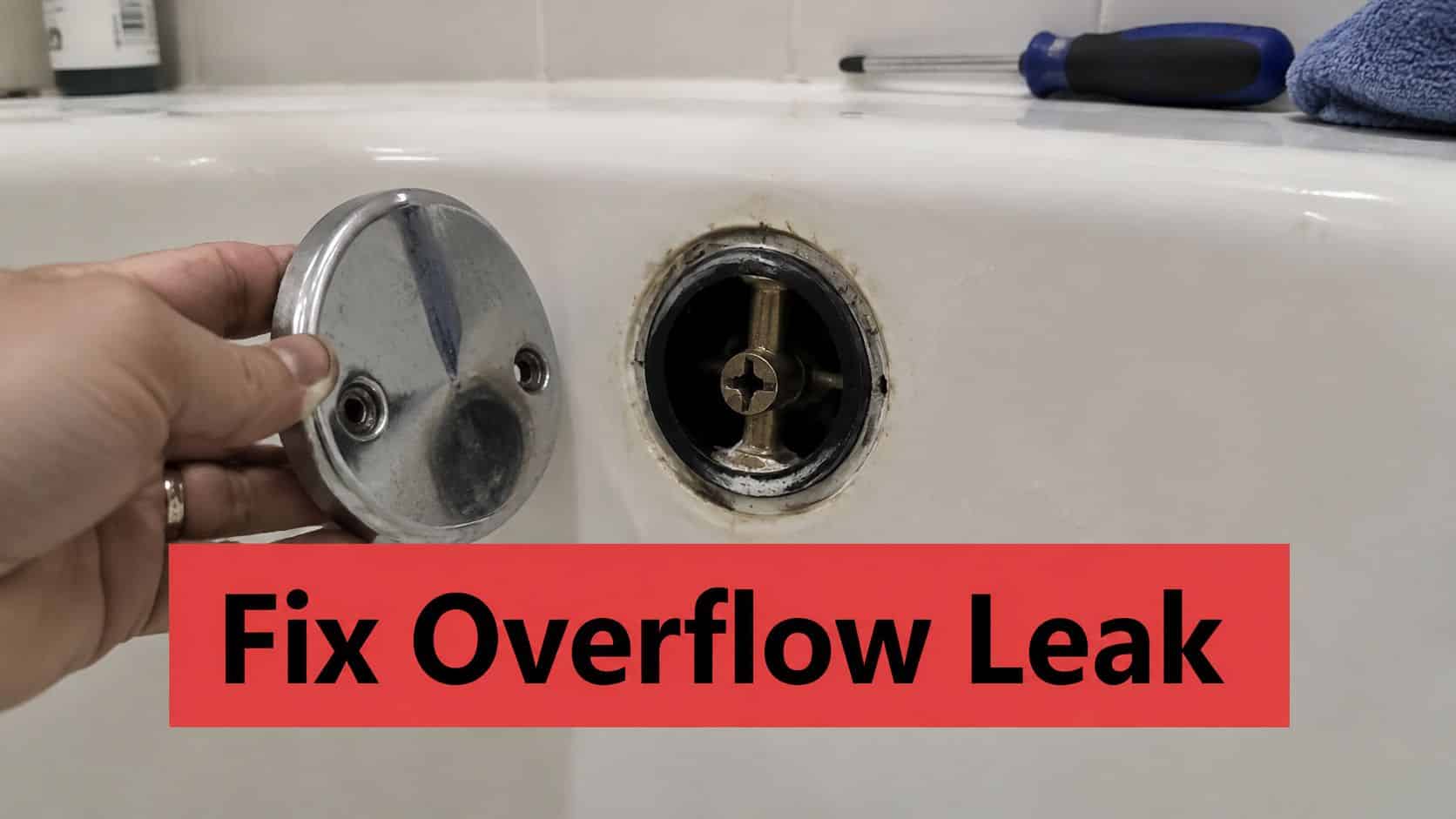 A person holding a chrome bathtub overflow cover plate next to the open drain assembly.